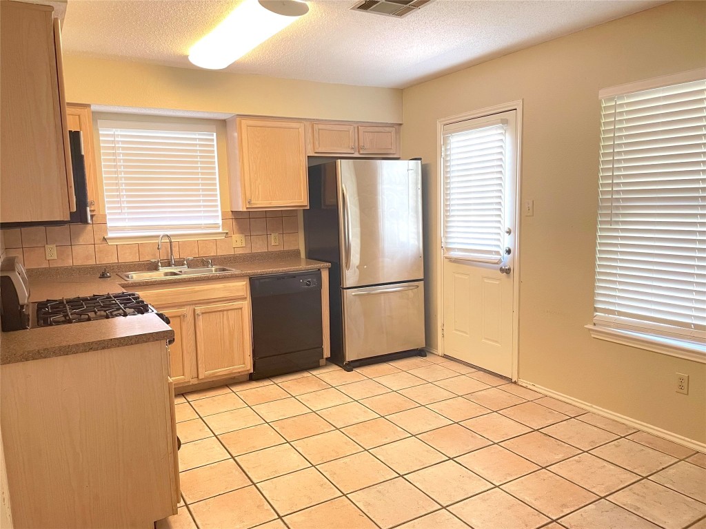 8501 Bismark Cove Austin, TX 78745 - Photo 10 of 24 a kitchen with a refrigerator sink stove and cabinets