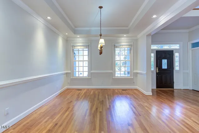 a view of a room with wooden floor chandelier and kitchen view