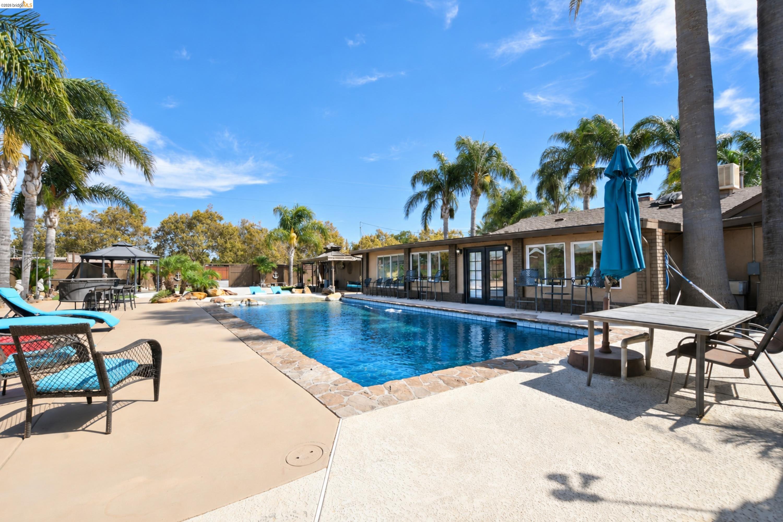 340 West Bolton Road Oakley, CA 94561 - Photo 64 of 87 Expansive backyard with a rectangular swimming pool, concrete patio, surrounding palm trees, and a built-in gazebo