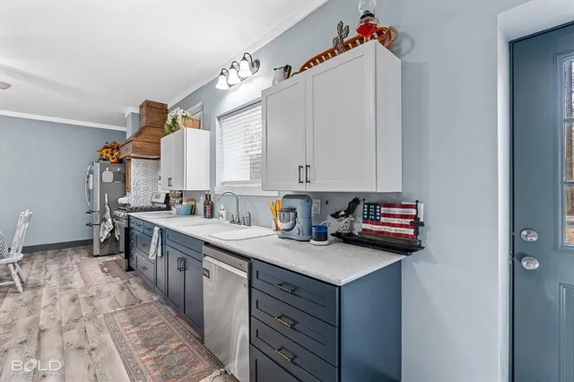 a kitchen with stainless steel appliances granite countertop a sink a stove a chimney a refrigerator and cabinets