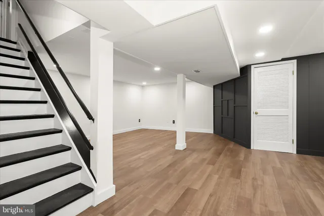 a view of an empty room with wooden floor and stairs