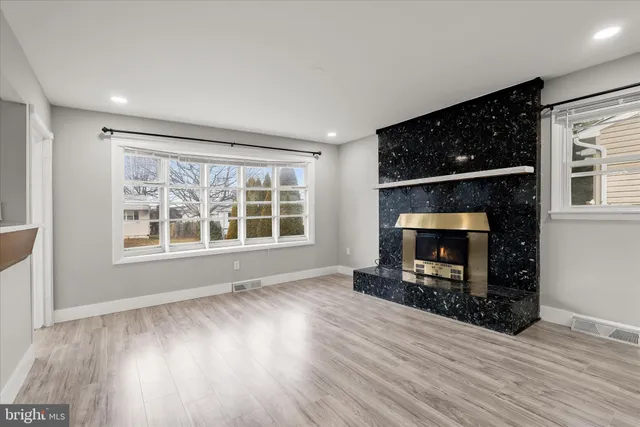 a view of an empty room with wooden floor fireplace and a window