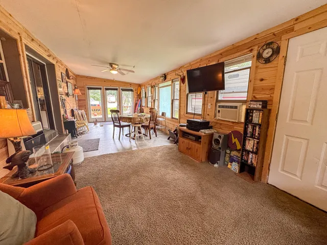 a living room with furniture two large window and a flat screen tv