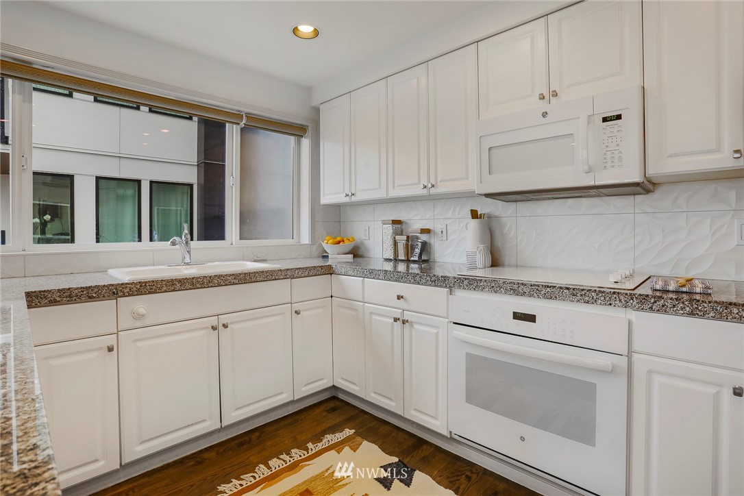 601 West Mercer Place, Unit 201 Seattle, WA 98119 - Photo 13 of 36 a kitchen with granite countertop white cabinets and white appliances