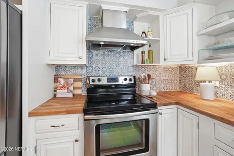 a kitchen with stainless steel appliances granite countertop white cabinets and a stove