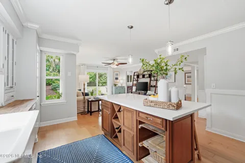 a open kitchen with stainless steel appliances granite countertop a sink dishwasher a stove a dining table and chairs with wooden floor