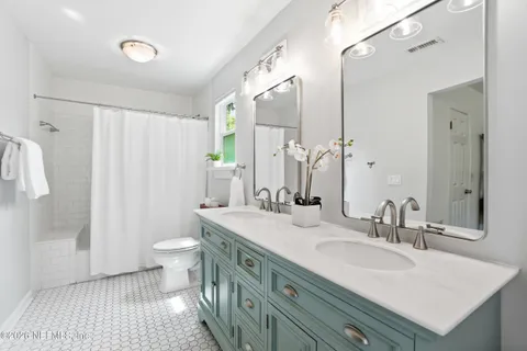a bathroom with a double vanity sink toilet and shower