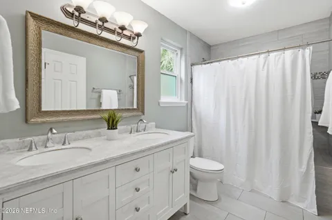 a bathroom with a granite countertop sink a toilet and a mirror