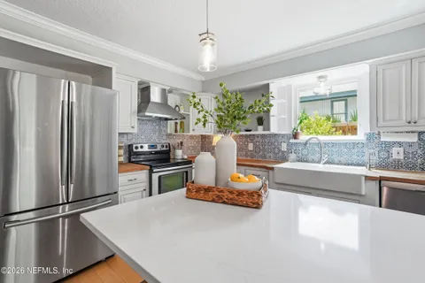 a kitchen with stainless steel appliances granite countertop a refrigerator a stove a sink and a granite counter tops with white cabinets