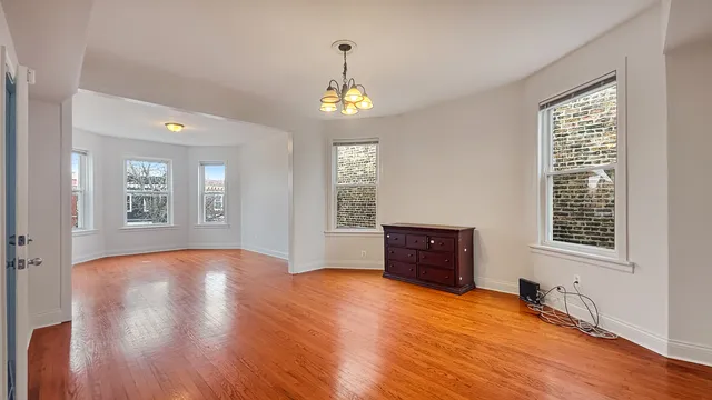 an empty room with wooden floor cabinet and windows