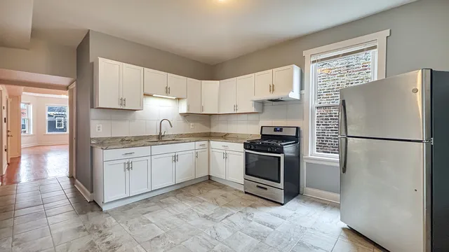 a kitchen with granite countertop a refrigerator stove top oven and sink