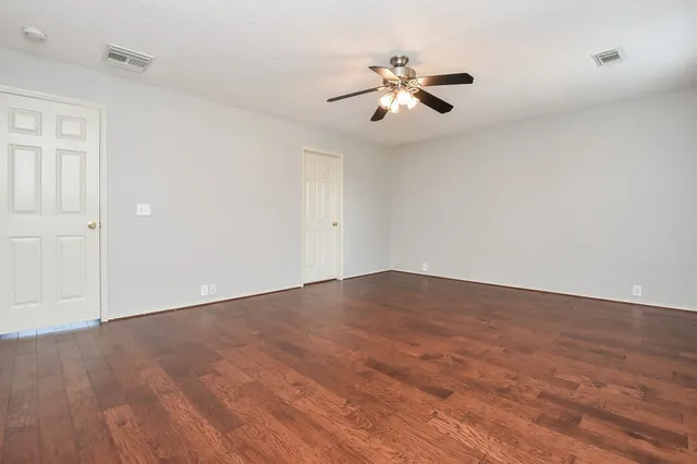 a view of empty room with wooden floor and fan