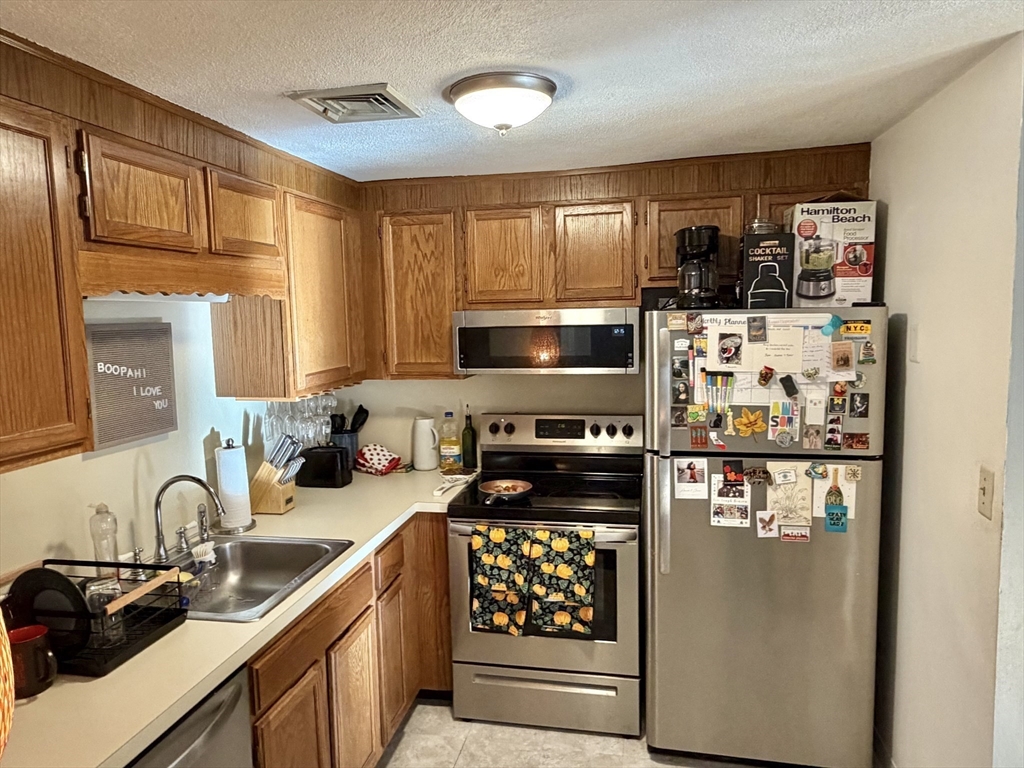 136 Central Street, Unit C 6 Hudson, MA 01749 - Photo 4 of 20 a kitchen with stainless steel appliances granite countertop a refrigerator a stove a sink and a microwave