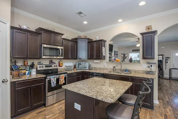 a kitchen with kitchen island granite countertop a sink stove and cabinets