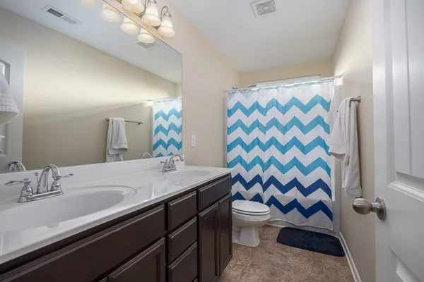 a bathroom with a sink a toilet a mirror and shower curtain