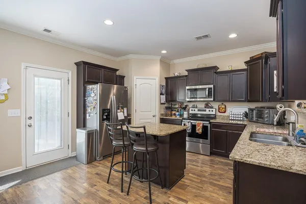 a kitchen with stainless steel appliances granite countertop a sink stove refrigerator and cabinets