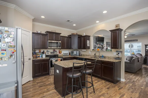 a kitchen with stainless steel appliances a sink a stove a refrigerator cabinets and a dining table