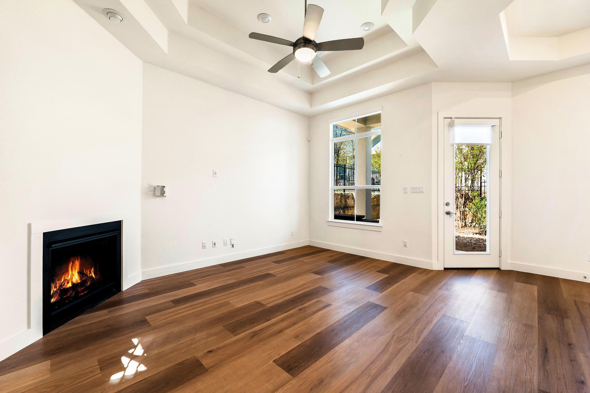 306 Cartwheel Bend, Unit 130 Austin, TX 78738 - Photo 23 of 40 a view of an empty room with wooden floor fireplace and a window