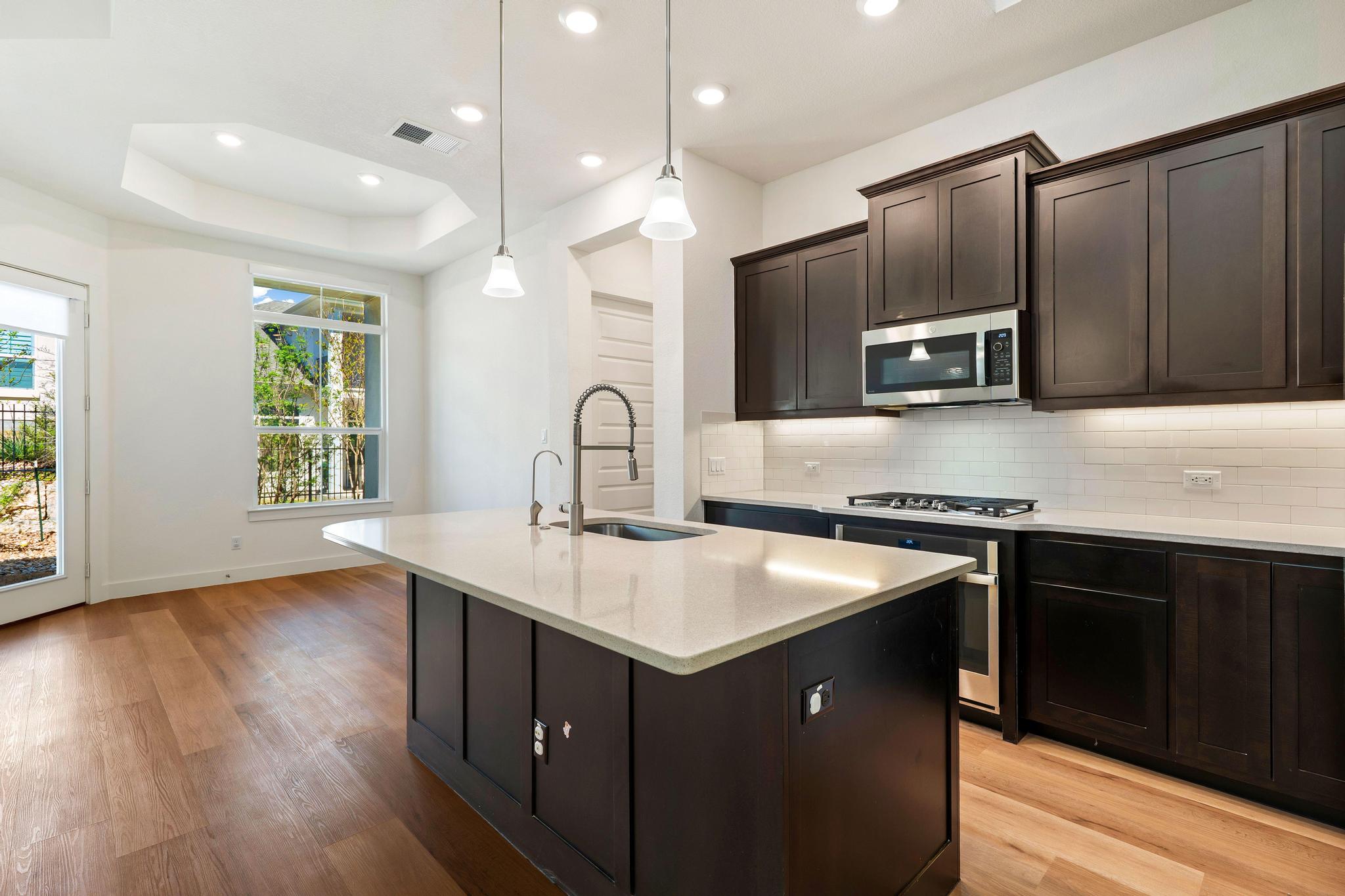 306 Cartwheel Bend, Unit 130 Austin, TX 78738 - Photo 27 of 40 a kitchen with a sink stove and microwave