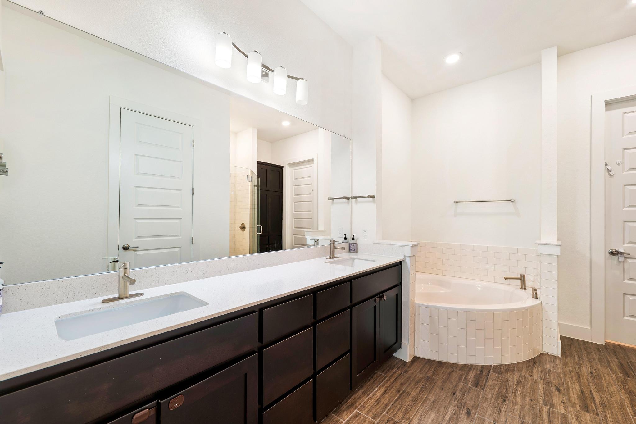 306 Cartwheel Bend, Unit 130 Austin, TX 78738 - Photo 29 of 40 a bathroom with a double vanity sink a mirror and a bathtub