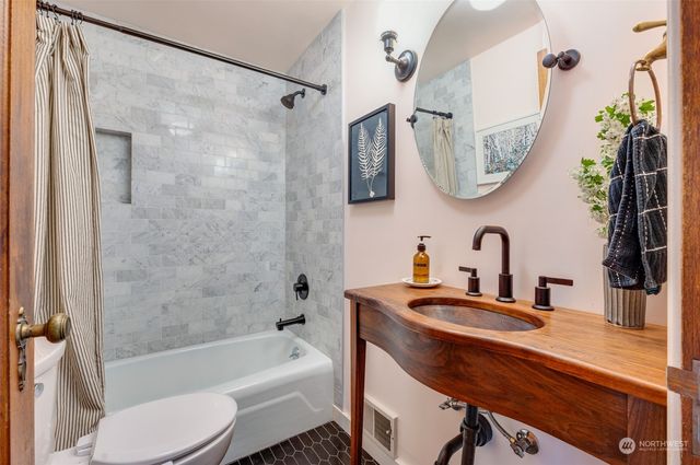 a bathroom with a sink a toilet a mirror a bathtub and shower