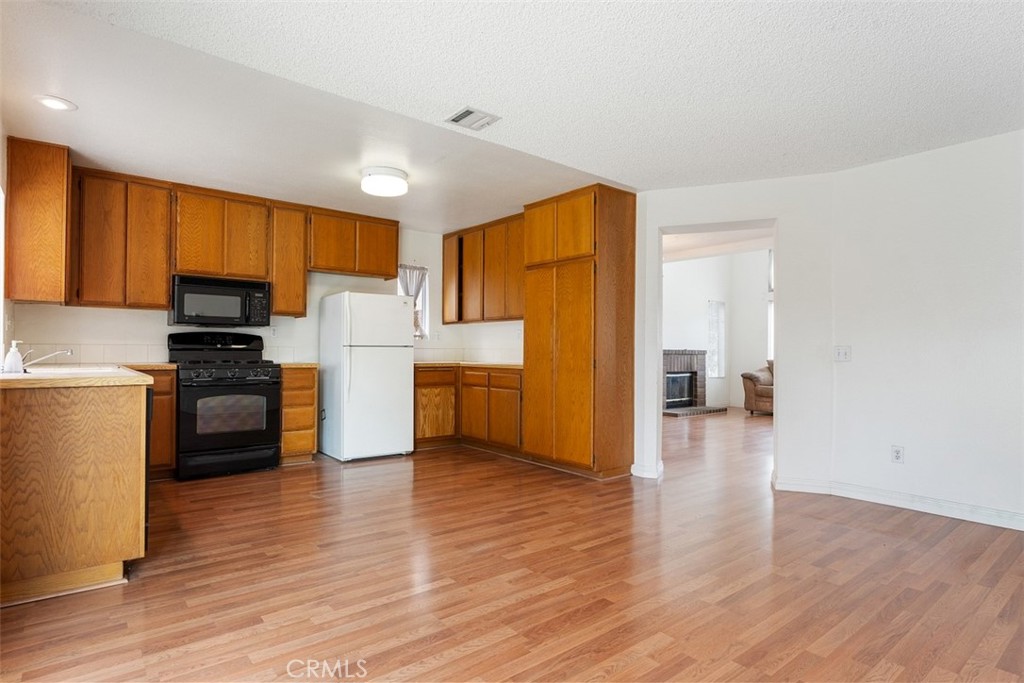 7040 Marino Place Rancho Cucamonga, CA 91701 - Photo 11 of 45 a kitchen with a refrigerator a stove top oven and wooden floor