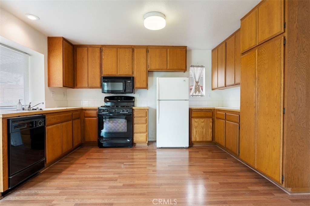 7040 Marino Place Rancho Cucamonga, CA 91701 - Photo 12 of 45 a kitchen with granite countertop wooden floors a stove and a refrigerator