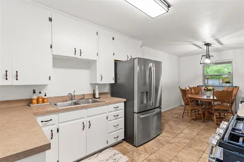 a kitchen with a refrigerator a stove a dining table and chairs with wooden floor