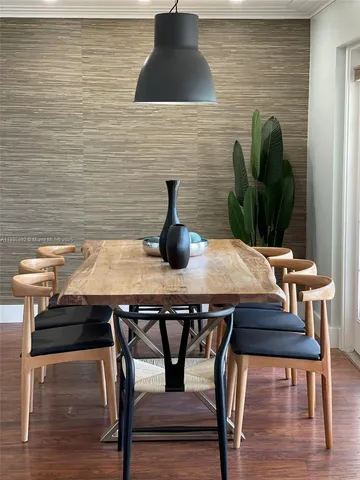 a table with chairs and a potted plant on wooden floor