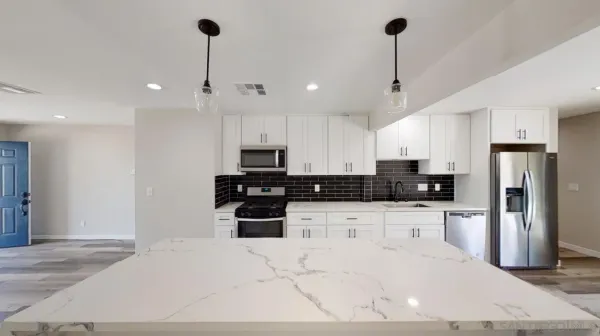 a view of a kitchen with stainless steel appliances kitchen island granite countertop a refrigerator a stove a sink a oven and a sink with wooden floor