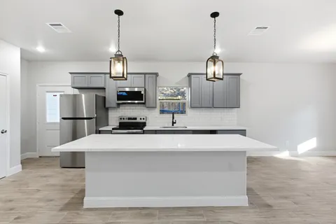 a kitchen with kitchen island a counter top space a sink stainless steel appliances and cabinets
