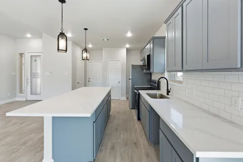 a very nice looking kitchen with kitchen island a sink a counter space and stainless steel appliances