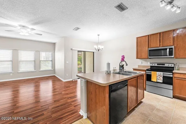 a large kitchen with kitchen island granite countertop a stove top oven a sink dishwasher a dining table and chairs with wooden floor