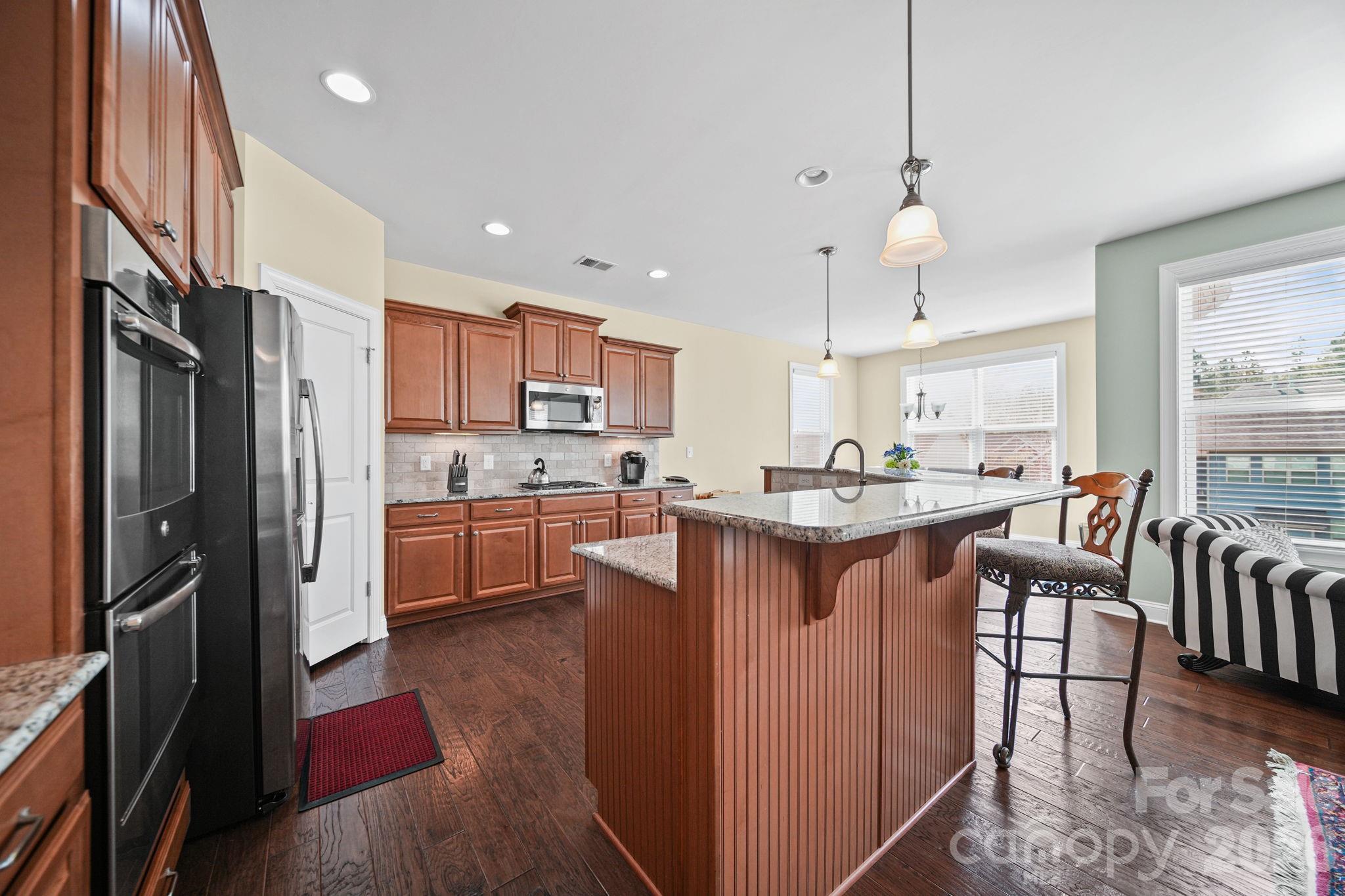 9639 Lockwood Road Concord, NC 28027 - Photo 16 of 33 a kitchen with kitchen island granite countertop a refrigerator a sink dishwasher a stove and white cabinets with wooden floor