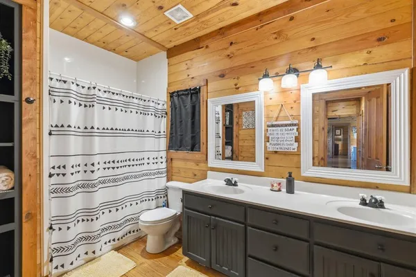 a bathroom with a double vanity sink toilet mirror and shower