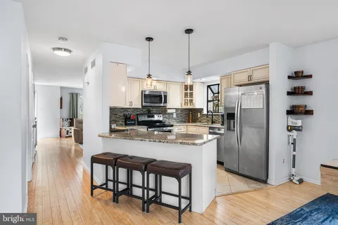 a kitchen with stainless steel appliances a refrigerator a stove a sink dishwasher and a dining table with wooden floor