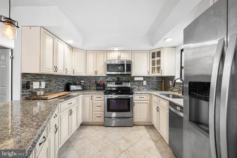 a kitchen with stainless steel appliances granite countertop a stove top oven a sink and dishwasher a refrigerator with white cabinets