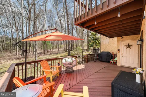 a view of a patio with table and chairs under an umbrella with a barbeque