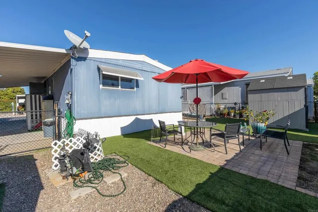 a view of a patio with couches table and chairs under an umbrella