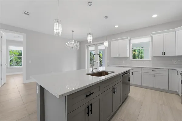 a kitchen with a sink dishwasher and white cabinets with wooden floor