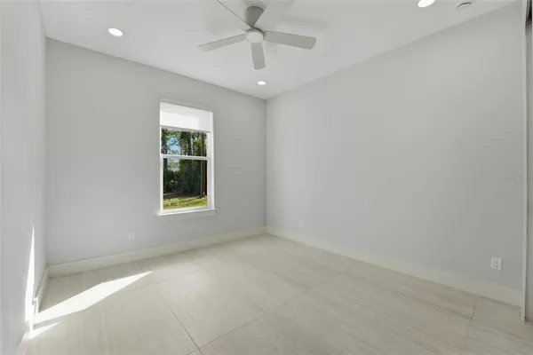 en empty room with windows and chandelier fan