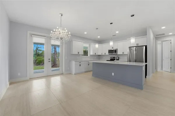 a large kitchen with stainless steel appliances kitchen island a large counter top a sink cabinets and a chandelier