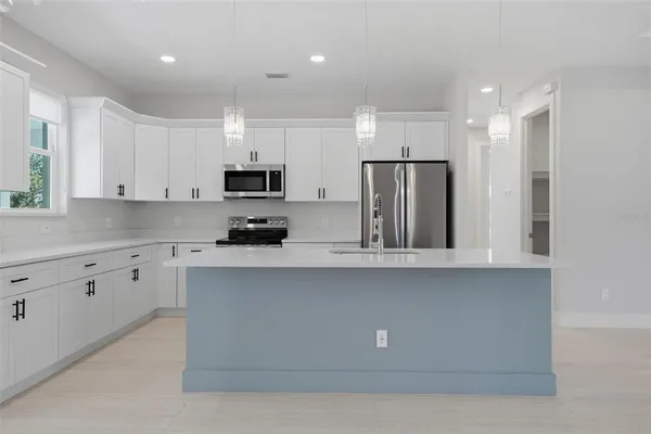 a kitchen with stainless steel appliances granite countertop a refrigerator a stove a sink and white cabinets