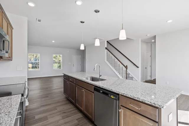 a view of empty room with wooden floor and kitchen