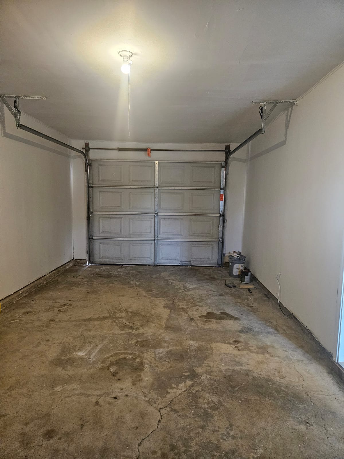 1401 Trinity Street Lockhart, TX 78644 - Photo 23 of 31 Single-car garage featuring a sectional garage door, concrete flooring, painted white walls, and an overhead light fixture