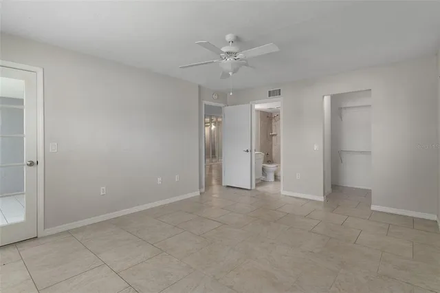 an empty room with windows and ceiling fan