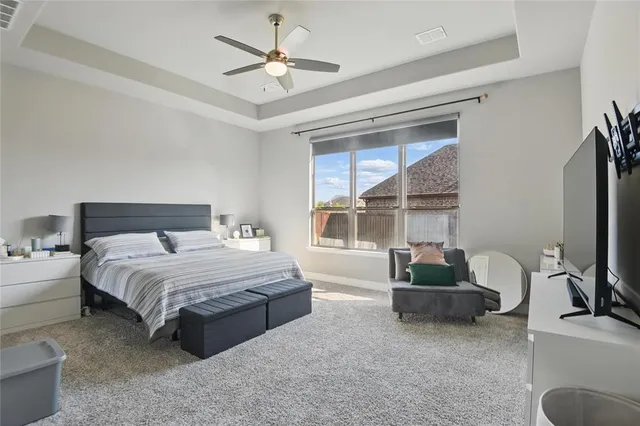 a spacious bedroom with a bed a couch and a flat tv screen
