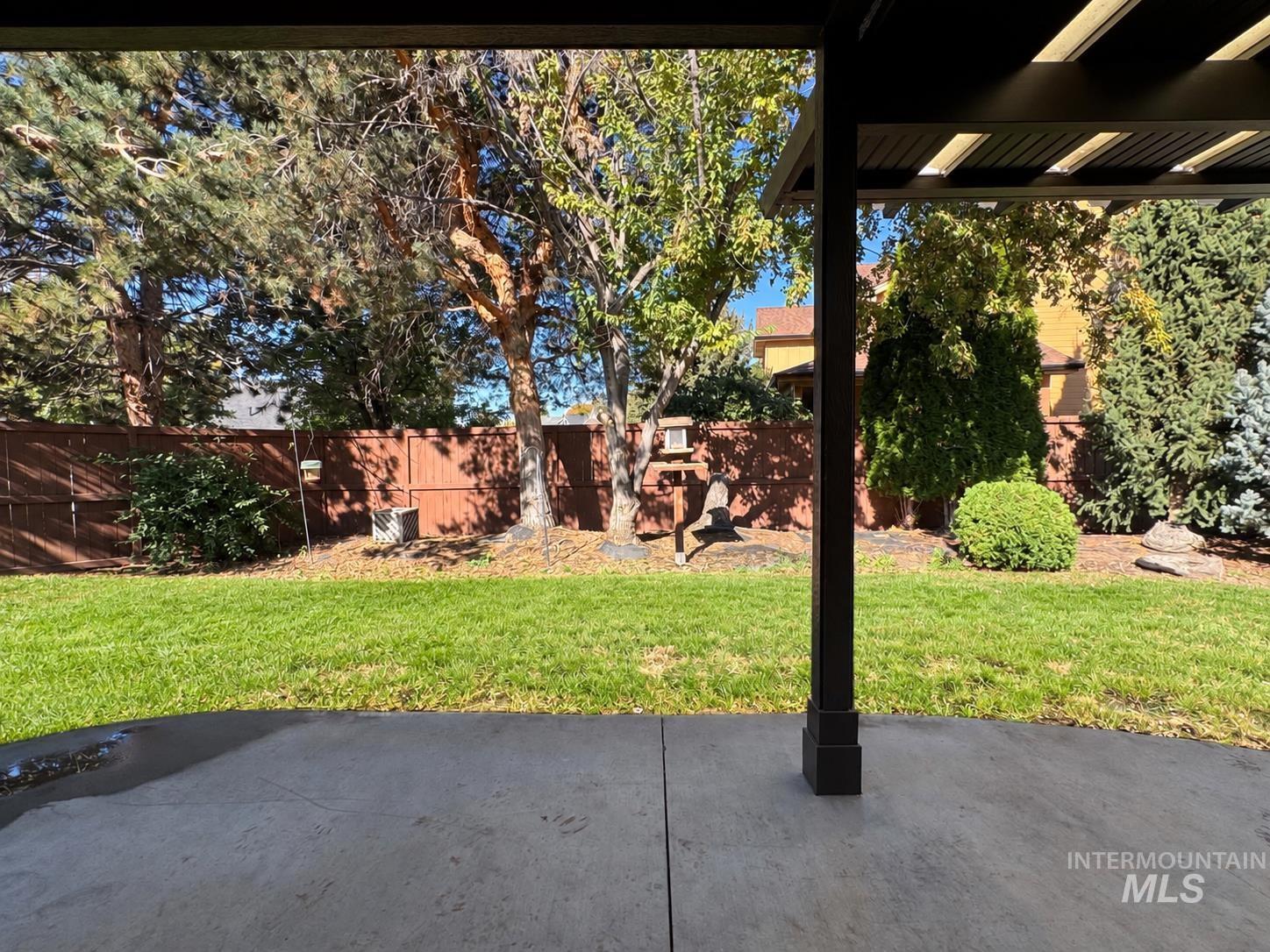 3917 North Waterloo Way Boise, ID 83713 - Photo 23 of 24 Expansive concrete patio with a modern pergola, leading to a landscaped backyard featuring a manicured lawn, mature trees, and a privacy fence