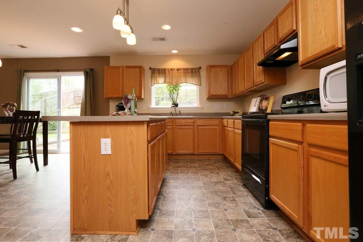 5944 Ricker Road Raleigh, NC 27610 - Photo 13 of 25 a kitchen with stainless steel appliances granite countertop sink stove top oven and cabinets