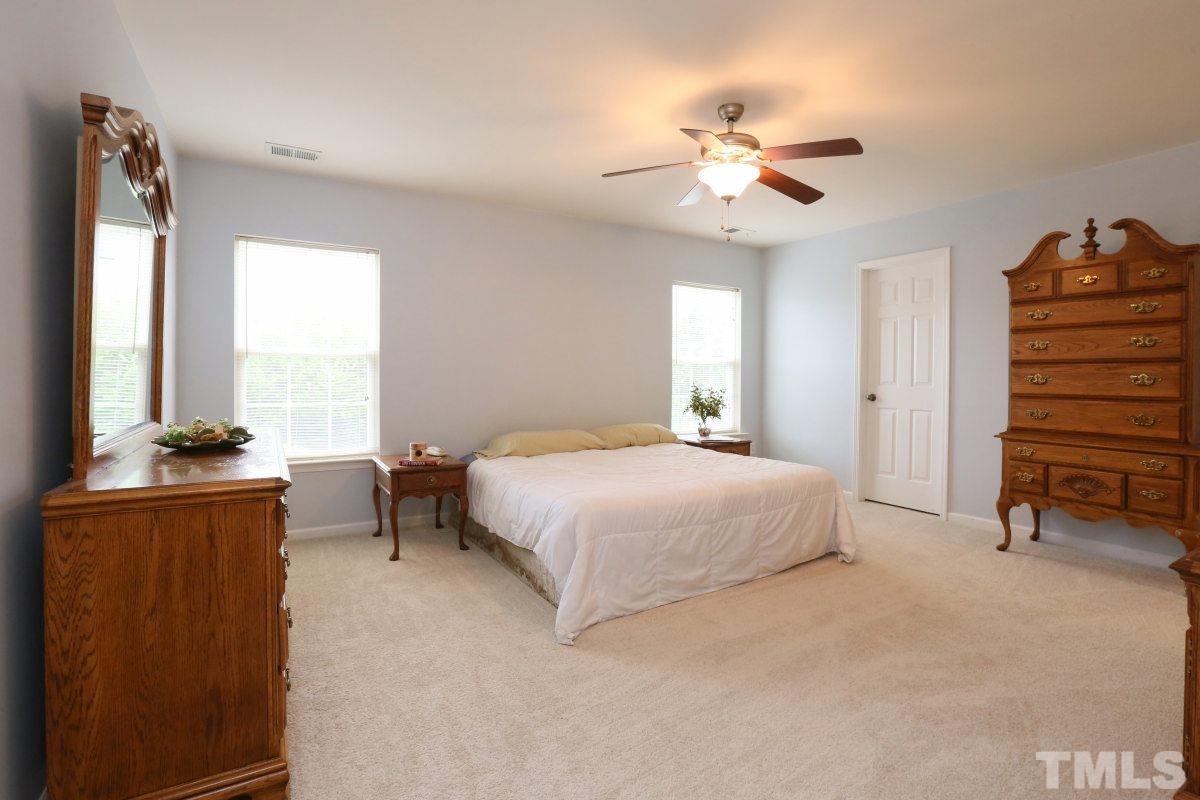 5944 Ricker Road Raleigh, NC 27610 - Photo 16 of 25 a bedroom with a bed and a chandelier
